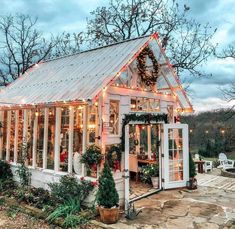 a small white house with christmas lights on it's roof and windows in the front