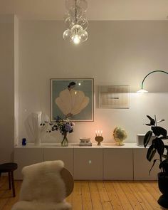 a living room filled with furniture and a chandelier hanging from the ceiling next to a potted plant