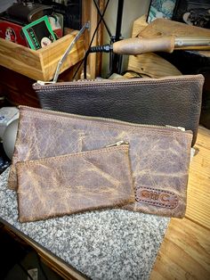 two brown leather wallets sitting on top of a counter next to a knife and other items