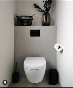 a white toilet sitting in a bathroom next to a black trash can