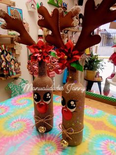 two decorated bottles sitting on top of a table covered in fake antlers and bows