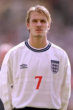 a male soccer player in a white shirt and black pants is looking at the camera