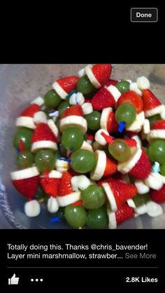 a plastic bowl filled with fruit and veggies covered in santa's hats