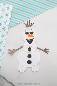 a close up of a paper snowman on top of a piece of white paper