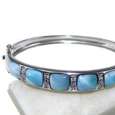 Oceanic Beauty of Larimar The oceanic beauty and the mysteries of the sea are perfectly captured in this stunning Larimar Ocean Bracelet. Accented with a cushion-cut Larimar gemstone this bracelet will surely make a lasting impression. Classic, timeless, yet so unique, just like you. We promise: the compliments will never stop coming! Unique and Spiritual Stone The Larimar stone used in each piece has its own pattern and contains different hues, varying from light blue to blue-green, making each Ocean Bracelet, Larimar Bracelet, Dragon Heart, Larimar Jewelry, Larimar Stone, Rare Gemstones, Silver Bangles, Stone Bracelet, Mother Earth