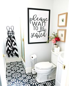 a white toilet sitting in a bathroom next to a black and white wall with a sign above it