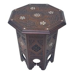 an octagonal wooden table with intricate carvings on the top and sides, in brown color