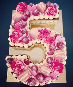 a cake shaped like the number five with flowers and hearts