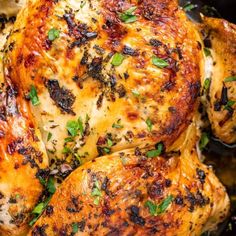 a close up of a chicken in a pan with herbs on the top and sides