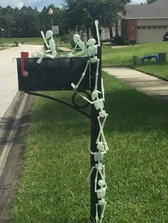 a mailbox decorated with skeletons and stringing on the grass in front of a house