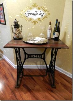 an old fashioned sewing table with wine bottles and other items on it in the corner of a room