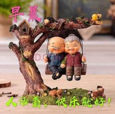 two figurines are sitting on a tree swing