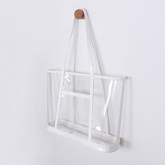 a clear plastic bag hanging on a white wall with a wooden button in the middle