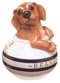 a ceramic figurine of a dog sitting on top of a ball that says beans