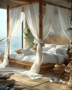 a bed with white drapes and pillows in a room next to the ocean,