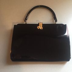 "This beautiful black handbag is in good vintage condition with very little wear. Very clean. Black stones in the ribbon like clasp adds elegant detail. Inner pocket lined in cream material and is the perfect size for a compact or lipstick. Short handle and patent leather type exterior, unknown material list. Label is slightly worn, but you can still read L & M and made in the USA. 9\" x 6\"" Hand Clutch, Oval Picture Frames, Black Stones, Silver Vase, Cycling Cap, Black Handbag, Black Purse, Black Purses, Black Stone