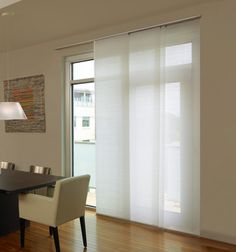 a dining room table with white chairs and a light hanging from it's ceiling