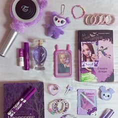 the contents of a purse laid out on top of a white table with purple accessories