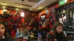 people sitting at tables in a restaurant with many decorations on the wall and behind them