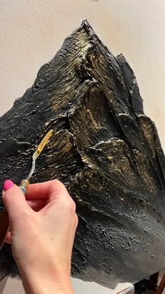 a person is painting a mountain with gold paint