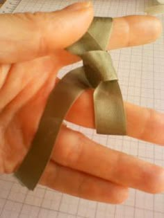 a person is holding a green ribbon in their left hand while making something out of paper