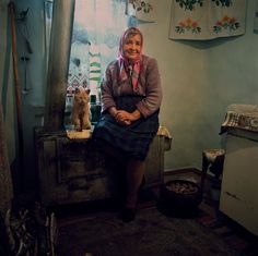 a woman sitting on top of a wooden bench next to a cat in a room