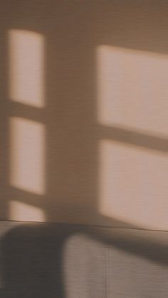 a person sitting on a couch with their feet propped up against the wall, in front of two windows