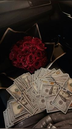 roses and cash are sitting in the back seat of a car, next to a bouquet of red roses