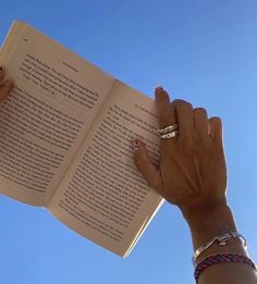 a woman is holding an open book in her left hand and reading it with both hands