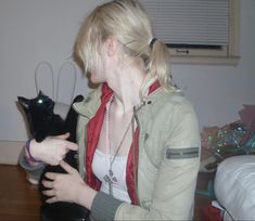 a woman holding a black cat in her hands