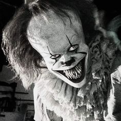 a creepy clown with big teeth and an evil look on his face is shown in black and white