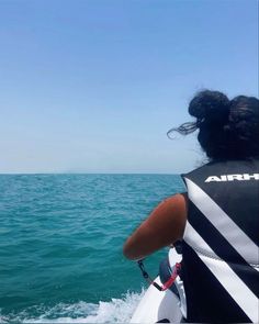 a woman riding on top of a boat in the ocean