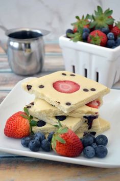 some strawberries and blueberries are on a white plate