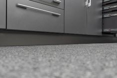 a kitchen with gray cabinets and drawers on the floor next to a stove top oven