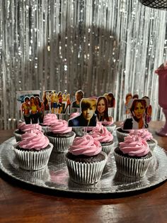 cupcakes with pink frosting and pictures on the top are sitting on a plate