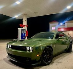 a green car parked in front of a gas station