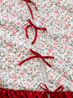 a red ribbon is tied to the side of a white and red flowered dress