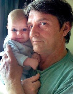 a man holding a baby in his arms and looking at the camera with an intense look on his face