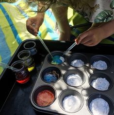 a woman is making cupcakes with icing and colored powder in the pan