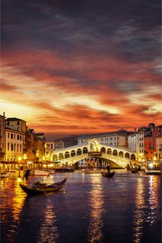 the city is lit up at night with boats on the water