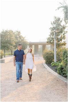 a man and woman walking down a path holding hands