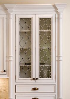 a white cabinet with glass doors in a kitchen