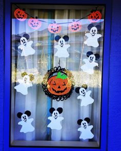 a window decorated for halloween with mickey mouse and pumpkins in the windowsill,