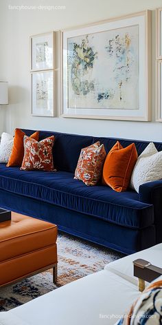 a living room with blue couches and orange pillows on the back of each couch