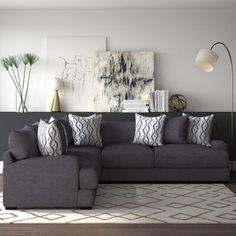 a living room with a large gray couch and white rugs on the hardwood floor