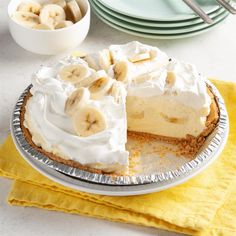 a banana cream pie on a table with plates and bowls