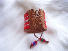 a brown leather case with red and white stripes on it sitting on a furry surface