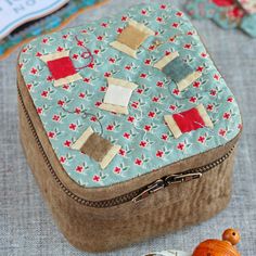 a sewing box with some small pieces of fabric on it and other items around it