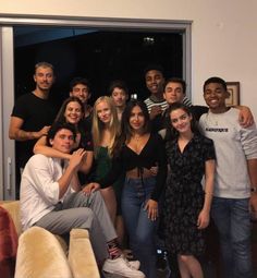 a group of young people posing for a photo in front of a door with their arms around each other