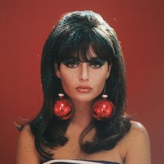 a woman with long black hair and red ornaments on her face, wearing large earrings